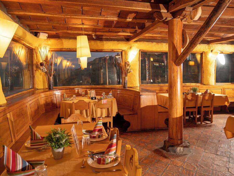 Un restaurante con interiores de madera, mesas dispuestas con servilletas a rayas y vistas amplias a través de grandes ventanales.