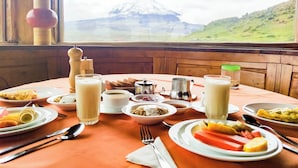 Una mesa dispuesta para el desayuno con vistas a una montaña nevada.