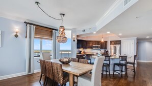 A spacious kitchen with dark wooden cabinets, stainless steel appliances, and a large island with seating. - The Pass 608 by Liquid Life (Orange Beach)