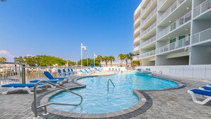 A pool area with blue lounge chairs, a pool ladder, and a building with balconies. - The Pass 608 by Liquid Life (Orange Beach)