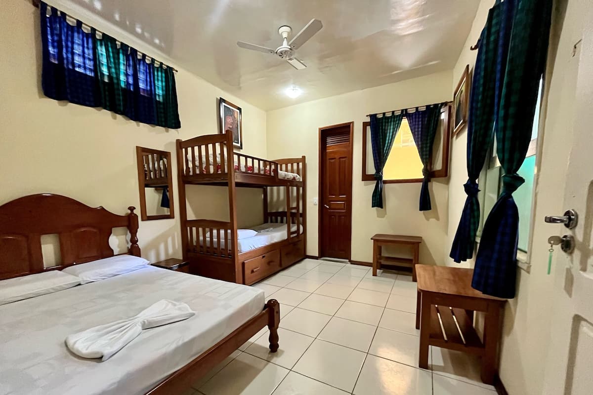 A room with bunk beds, a ceiling fan, a small table, and a door.