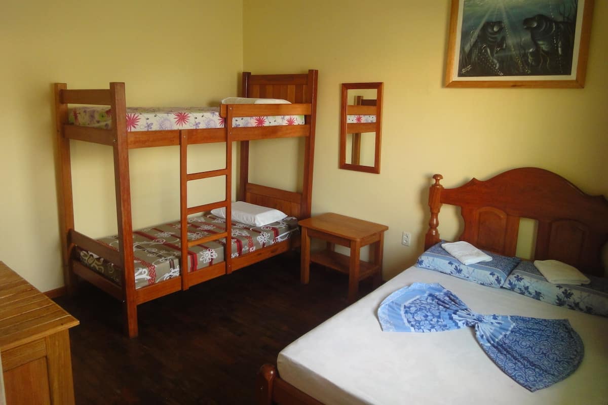 A bunk bed room with a wooden headboard, a bedside table, and a small mirror.