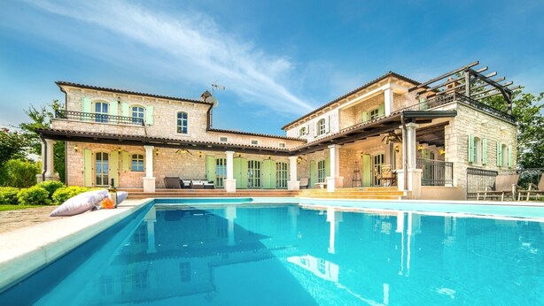 A two-story stone building with a swimming pool in front.