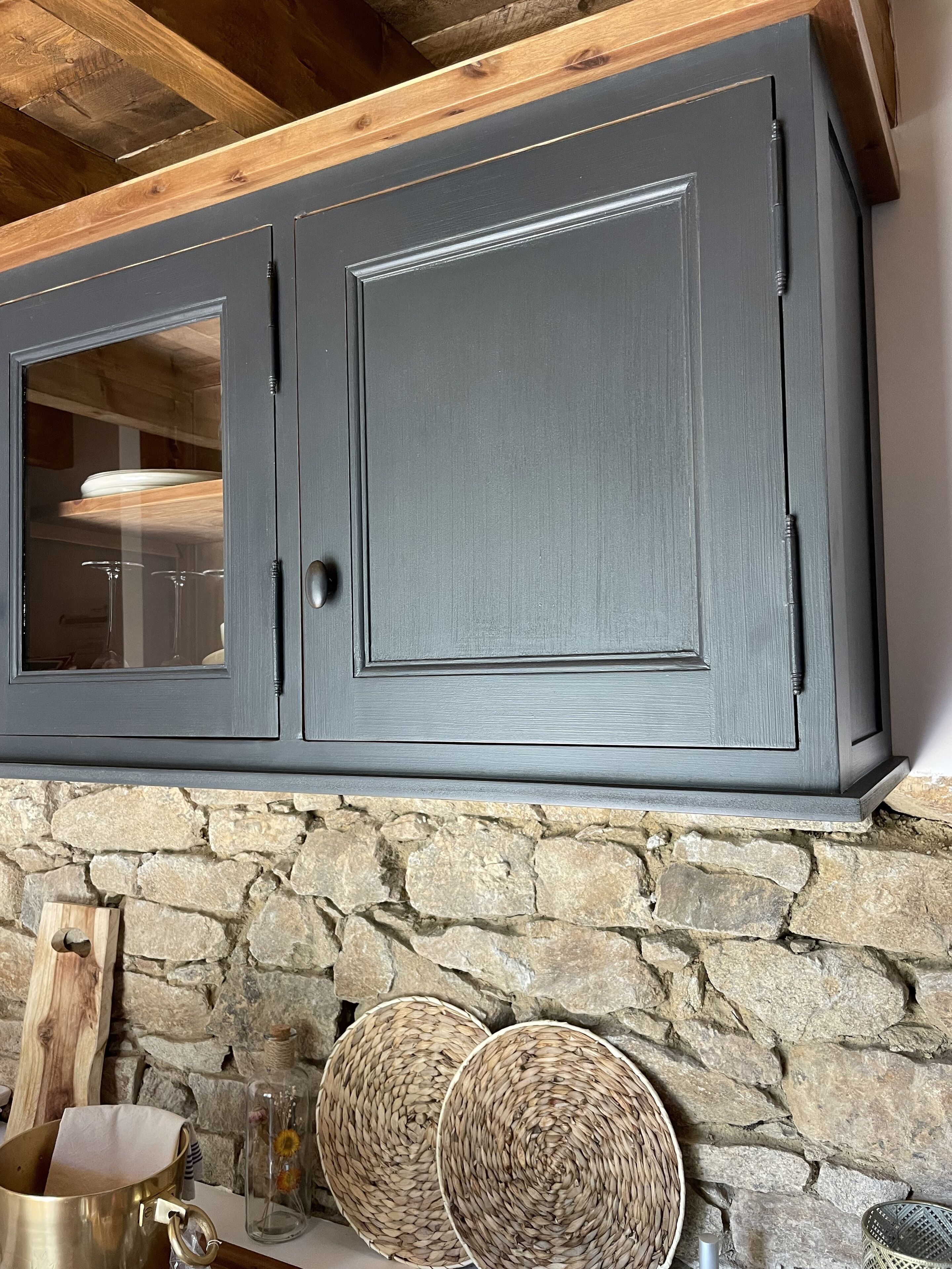 Una cocina con armarios gris oscuro, encimera de piedra y dos cestas tejidas.