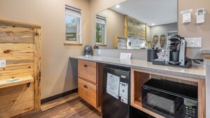 A compact kitchen with wooden cabinetry, a built-in microwave, a coffee maker, and a refrigerator.