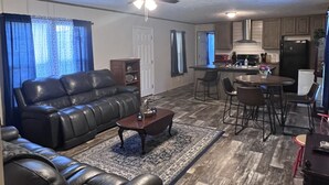 A living room with a sofa, coffee table, and dining area with chairs.