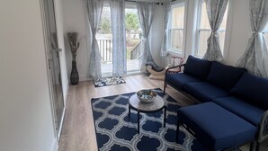 A living room with a blue sofa, a small round table with a bowl, and a patterned rug.