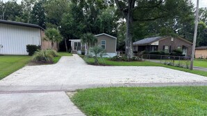 A residential street with houses, a driveway, and a grassy area.