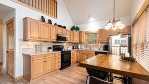 Una cocina moderna con armarios de madera, electrodomésticos de acero inoxidable y una mesa de comedor de madera.