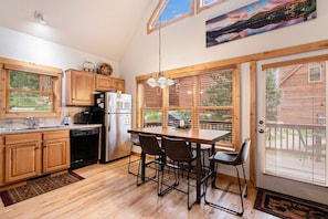 A kitchen with wooden cabinets, a dining table with chairs, a refrigerator, and a window with blinds.