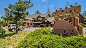 Una cabaña con un letrero que dice "VACATION RESORT NIGHTLY / WEEKLY" y "SOLITUDE" sobre una roca grande.