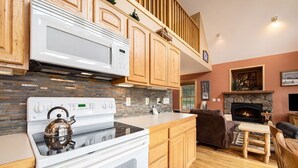 A kitchen with wooden cabinets, a white stove, and a stone fireplace.