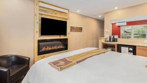 Hotellihuone, jossa on sänky, puukehystetty takka, televisio, kyltti, jossa lukee ”Seikkailu”, ja ikkuna, josta avautuu näkymä vehreään maisemaan.