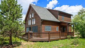 A two-story wooden cabin with a deck, surrounded by trees and under a clear sky. - Solitude Bobcat #6 - Estes Park 2 Bedroom Condo by RedAwning (Estes Park)