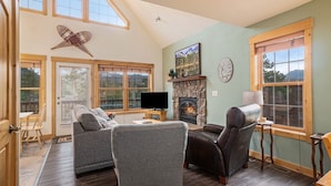 A cozy living room with a fireplace, comfortable seating, and large windows. - Solitude Eagle #2 - Estes Park 2 Bedroom Condo by RedAwning (Estes Park)