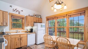 A kitchen with wooden cabinets, a refrigerator, a sink, and a dining table with chairs. - Solitude Eagle #2 - Estes Park 2 Bedroom Condo by RedAwning (Estes Park)