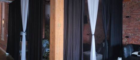 Une pièce avec un mur en briques, un plafond en bois et un canapé en cuir noir.