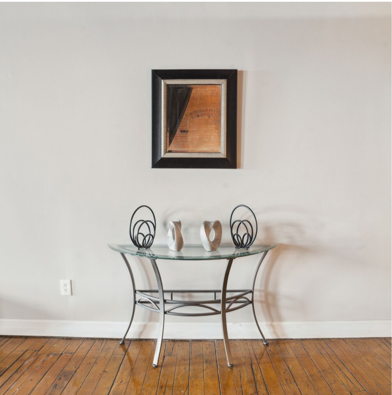 Een kamer met een tafel met glazen blad, metalen frame en twee wandlampen.