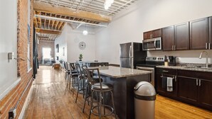 A modern kitchen with dark wooden cabinets, stainless steel appliances, and a central island with bar stools. - Downtown Detroit Loft - Fully equipped & Absolutely Gorgeous theme by RedAwning (Detroit)
