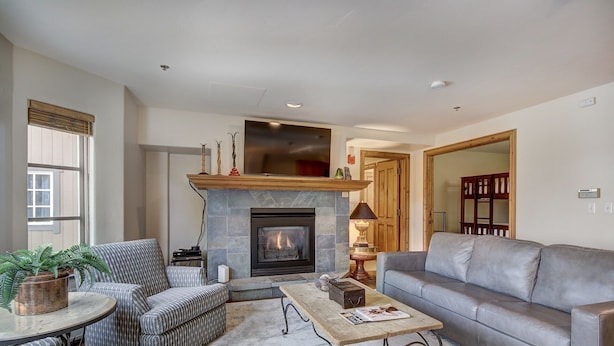 A living room with a fireplace, a sofa, a coffee table, and patterned chairs. - 1BR Plus Den, Heart of Beaver Creek Village 1 Bedroom Condo by RedAwning (Avon)