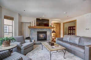 A living room with a fireplace, a sofa, a coffee table, and patterned chairs. - 1BR Plus Den, Heart of Beaver Creek Village 1 Bedroom Condo by RedAwning (Avon)