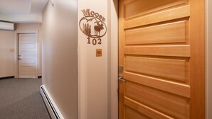 A hallway with a wooden door, a wall-mounted sign reading "Moose 102", and a carpeted floor.