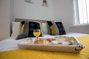 Enjoy a cozy morning in this stylishly appointed room, complete with a made bed and a tray of breakfast treats.