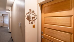 Ein Flur mit einer Holztür mit der Aufschrift „101“ und einer Wanddekoration mit einem Reh und Bäumen.