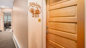 A hotel room with a wooden door, a wall-mounted number plate '203', and a glimpse of a dining area in the background. - Solitude Gem Lake 203 - Estes Park 1 Bedroom Studio by RedAwning (Estes Park)
