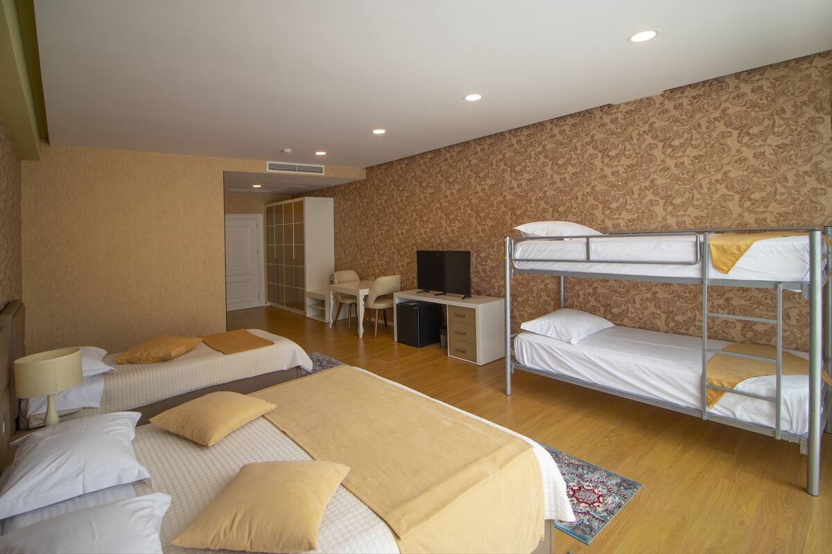 Une chambre d’hôtel avec des lits superposés, un bureau, une chaise et un téléviseur.