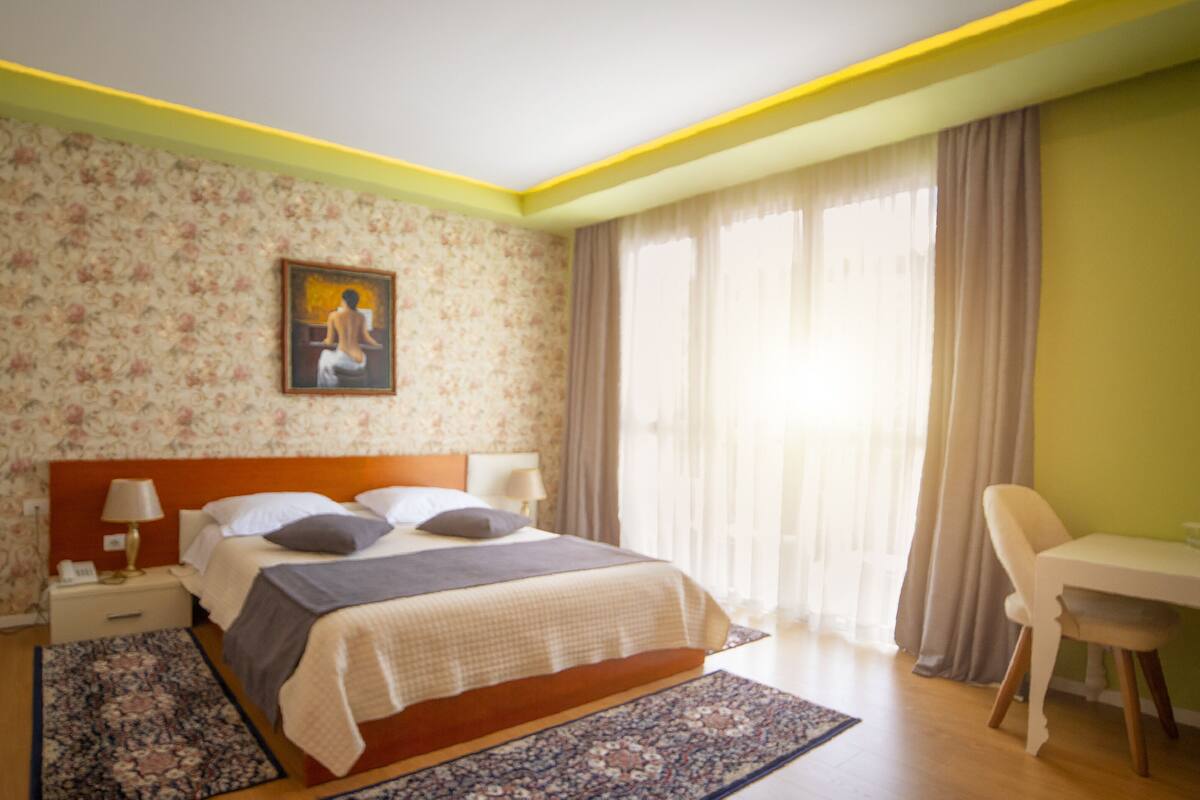 Une chambre d’hôtel avec un lit, des lampes de chevet, un bureau et une chaise.