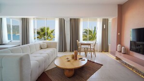 A modern living room with a sofa, a round wooden table, and a TV on the wall.