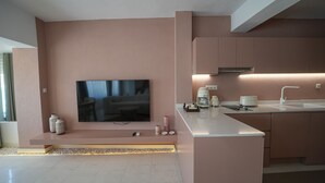 A modern kitchen with a flat-screen TV mounted on the wall, a built-in sink, and a coffee maker.
