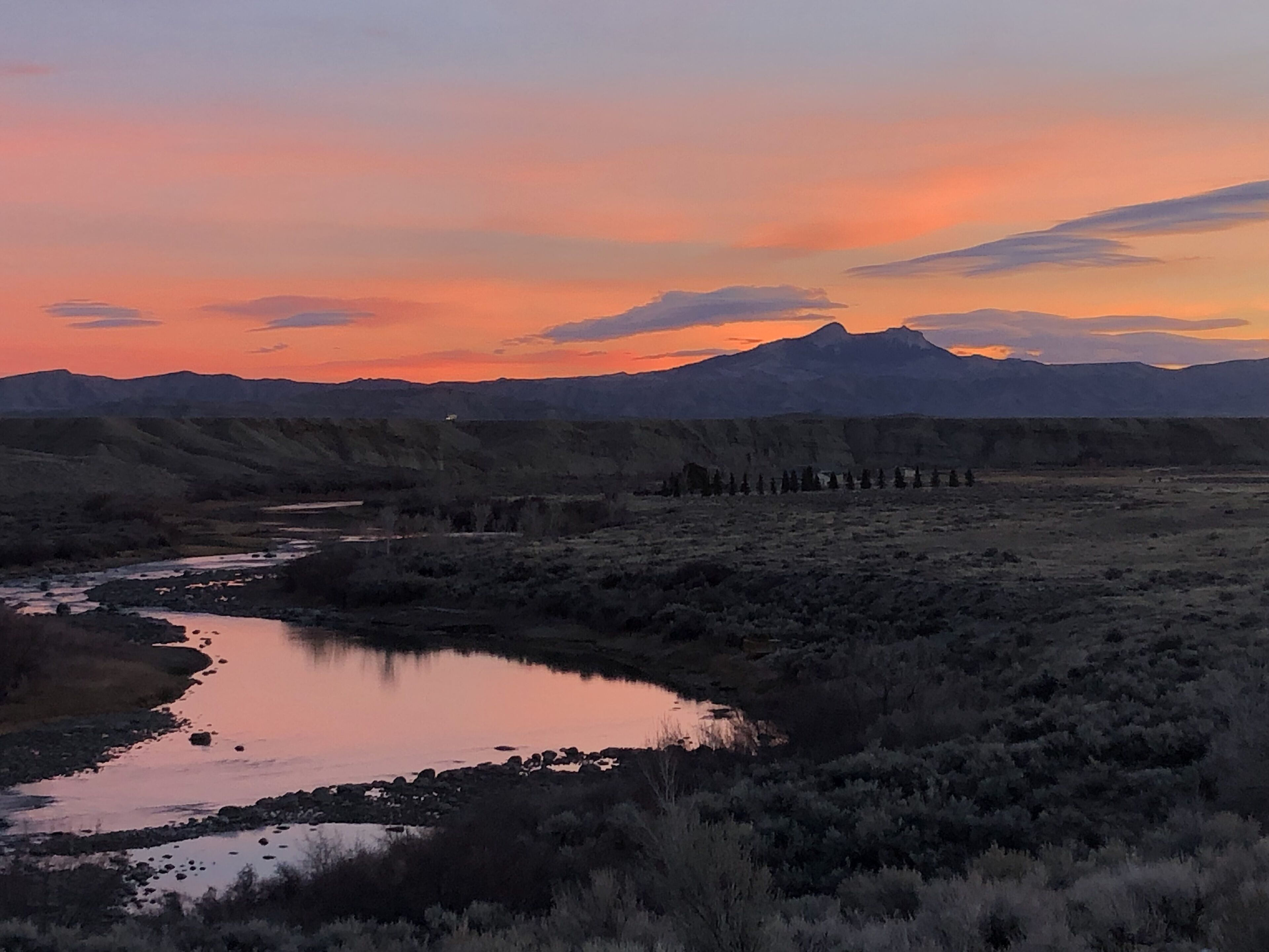 A landscape with a river, hills, and a mountain in the background.
