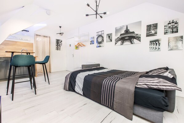 A compact bedroom with a bed, a desk, and two chairs.