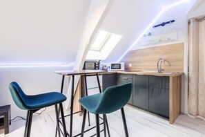 A modern kitchen with a wooden countertop, two bar stools, a built-in dishwasher, and a skylight.