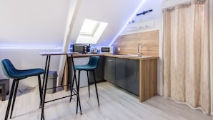 Et moderne køkken med ovenlys, to barstole, en mikroovn og en vask.