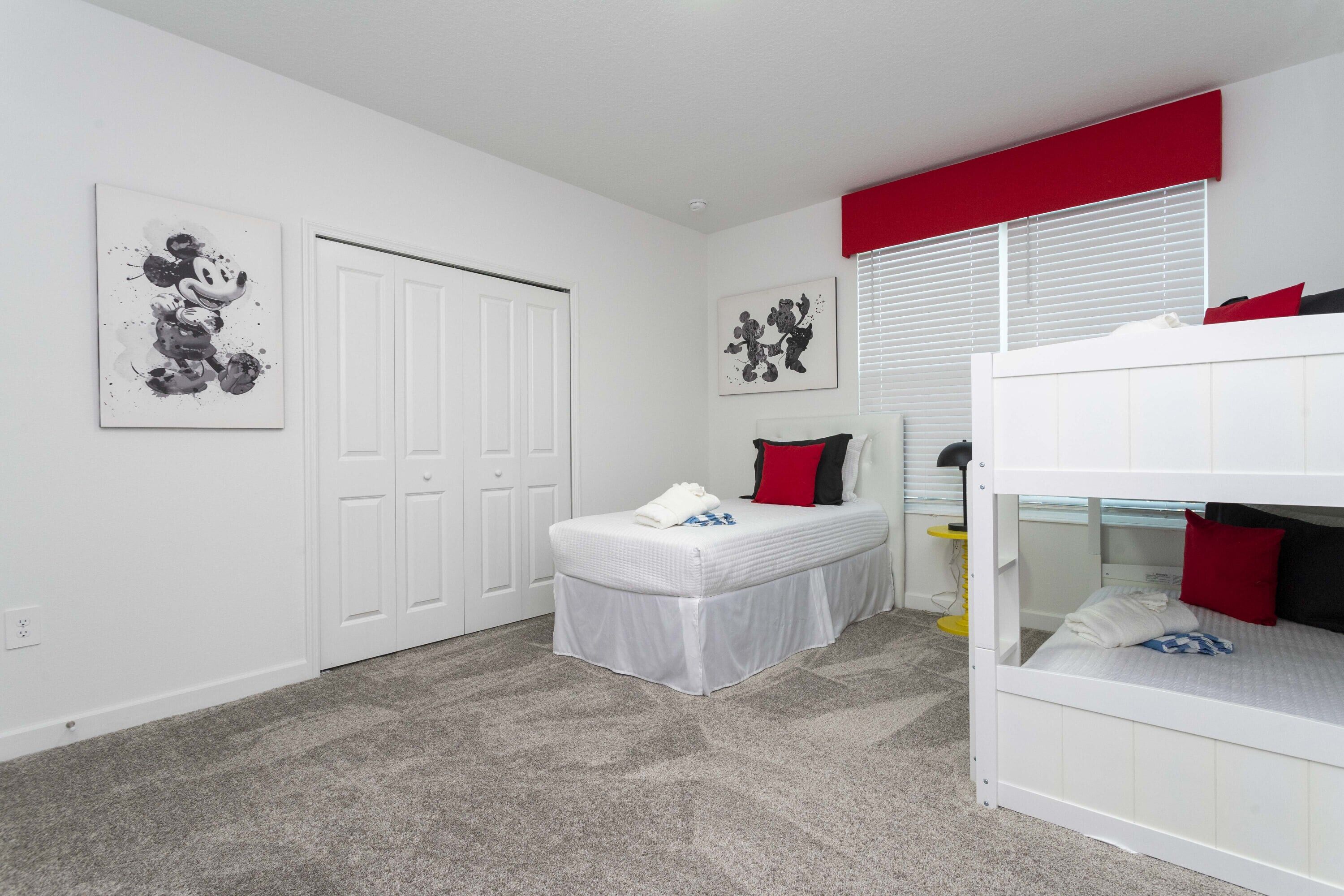 Een slaapkamer met een stapelbed, een enkel bed, een klein tafeltje en kunst aan de muren.