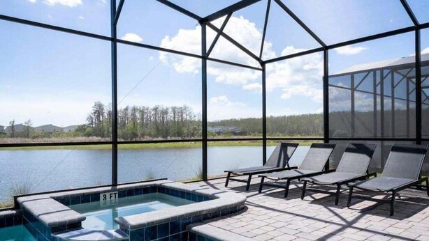 An outdoor swimming pool with lounge chairs, a hot tub, and a view of a lake and trees. - Last Minute Disney! Private Pool, Hot Tub, Game Room & Themed Bedrooms. Book Now! #90505 (Orlando)