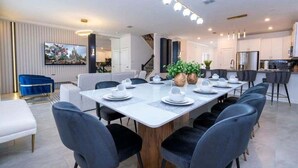 A modern dining area with a long table set for six, surrounded by dark chairs. - Last Minute Disney! Private Pool, Hot Tub, Game Room & Themed Bedrooms. Book Now! #90505 (Orlando)