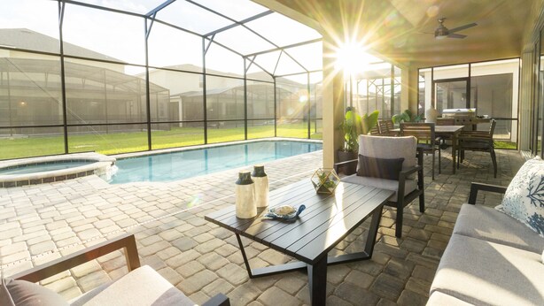 A covered patio with a pool, outdoor furniture, and a view of the backyard. - Last Minute Disney! Private Pool, Hot Tub, Game Room & Themed Bedrooms. Book Now! #90507 (Orlando)