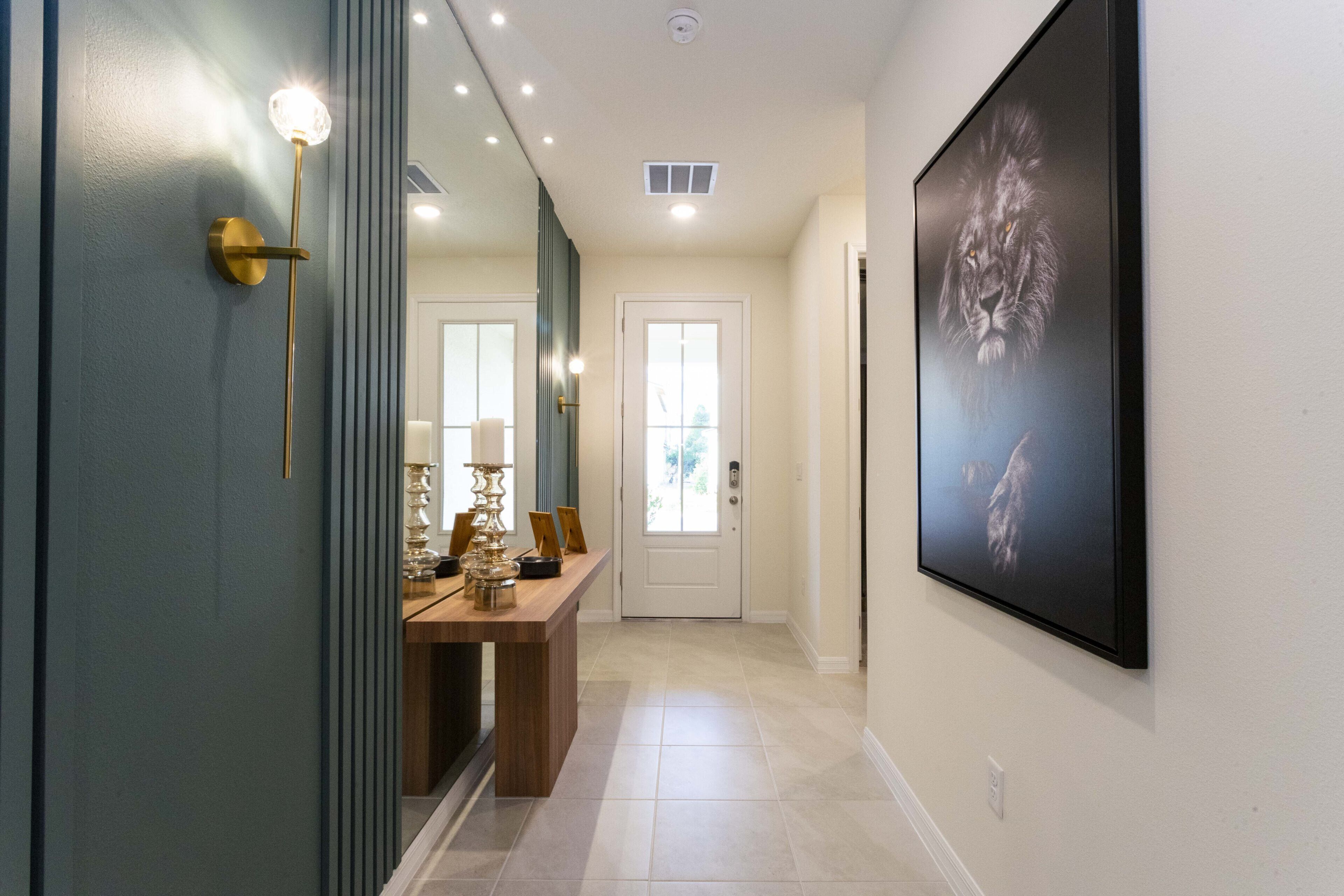 A hallway with a door, a framed picture, and a table with decorative items.