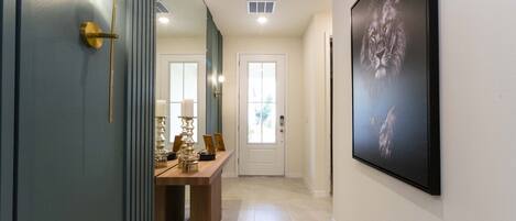A hallway with a door, a framed picture, and a table with decorative items.
