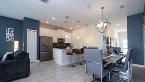 Una cocina moderna con una isla central, taburetes de bar y una mesa de comedor con sillas.