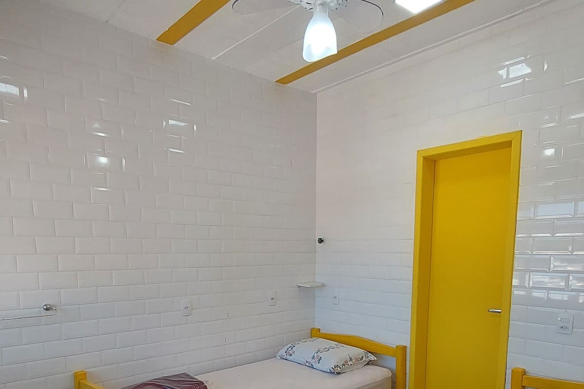 Una habitación con dos camas, un ventilador de techo y una puerta amarilla.