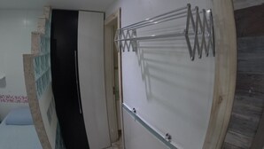 Una habitación con un tendedero empotrado, una puerta que da a otra estancia y un panel de madera en la pared.