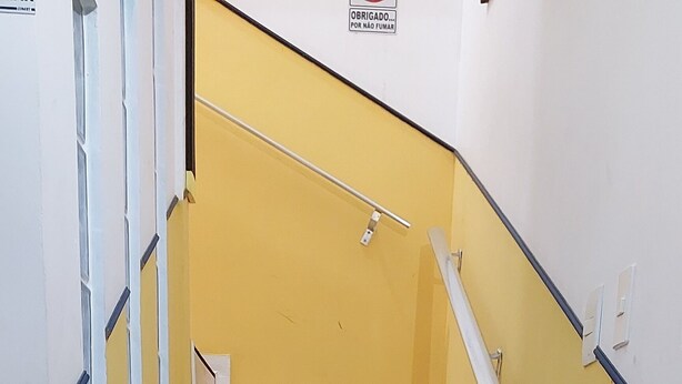 Una escalera de madera con barandillas blancas y una pared amarilla.