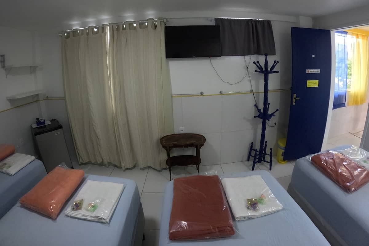 Una habitación de hotel con dos camas, televisión, perchero y una mesita.
