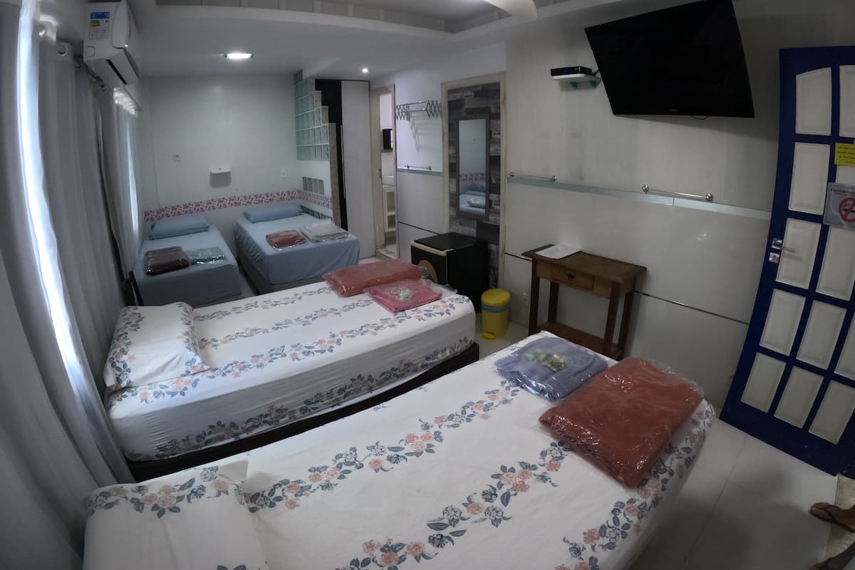 Habitación de hotel con dos camas, un ventilador de techo, un televisor montado en la pared y una puerta con cerradura de seguridad.