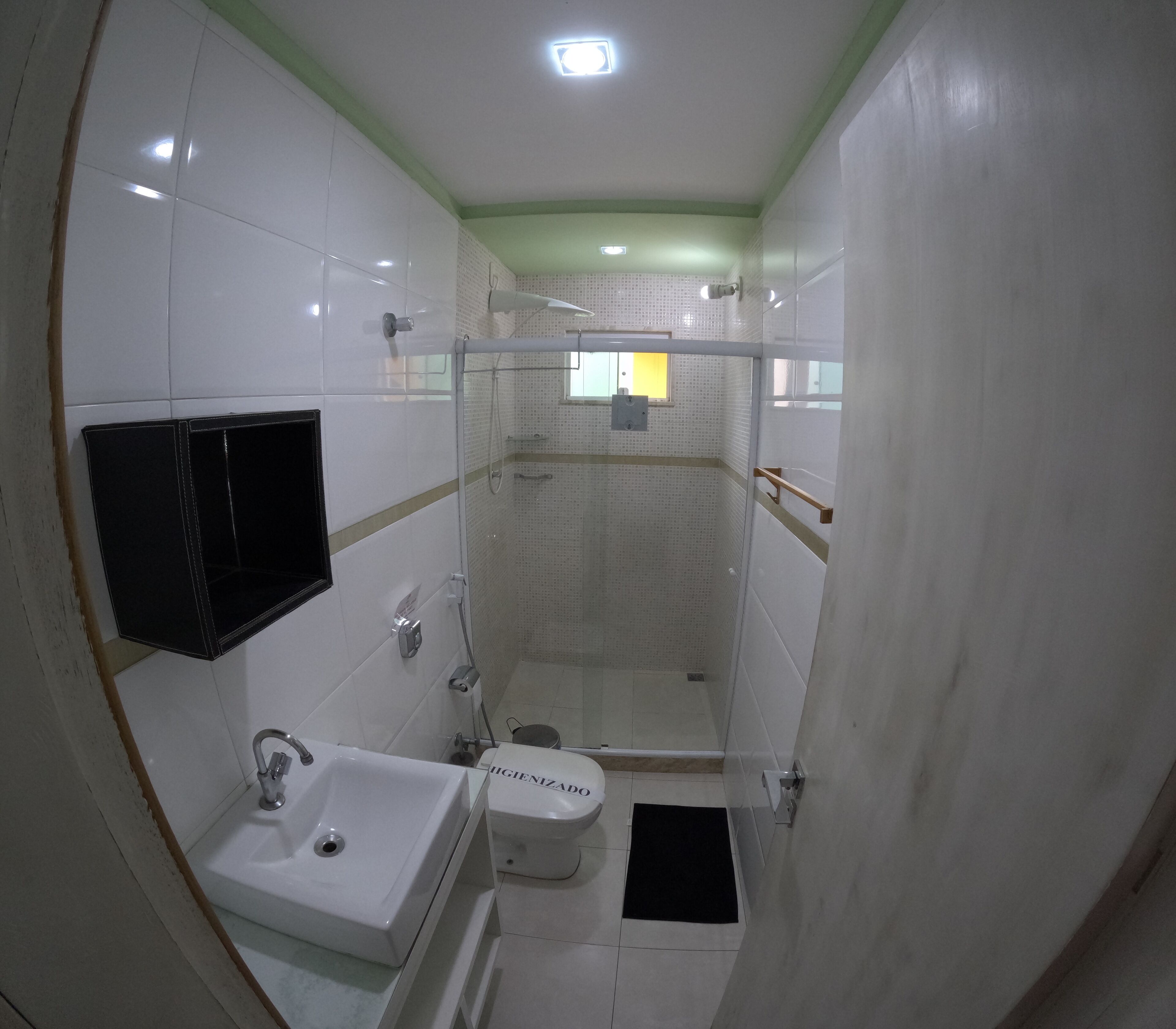 A compact bathroom with a white sink, toilet, and shower area.